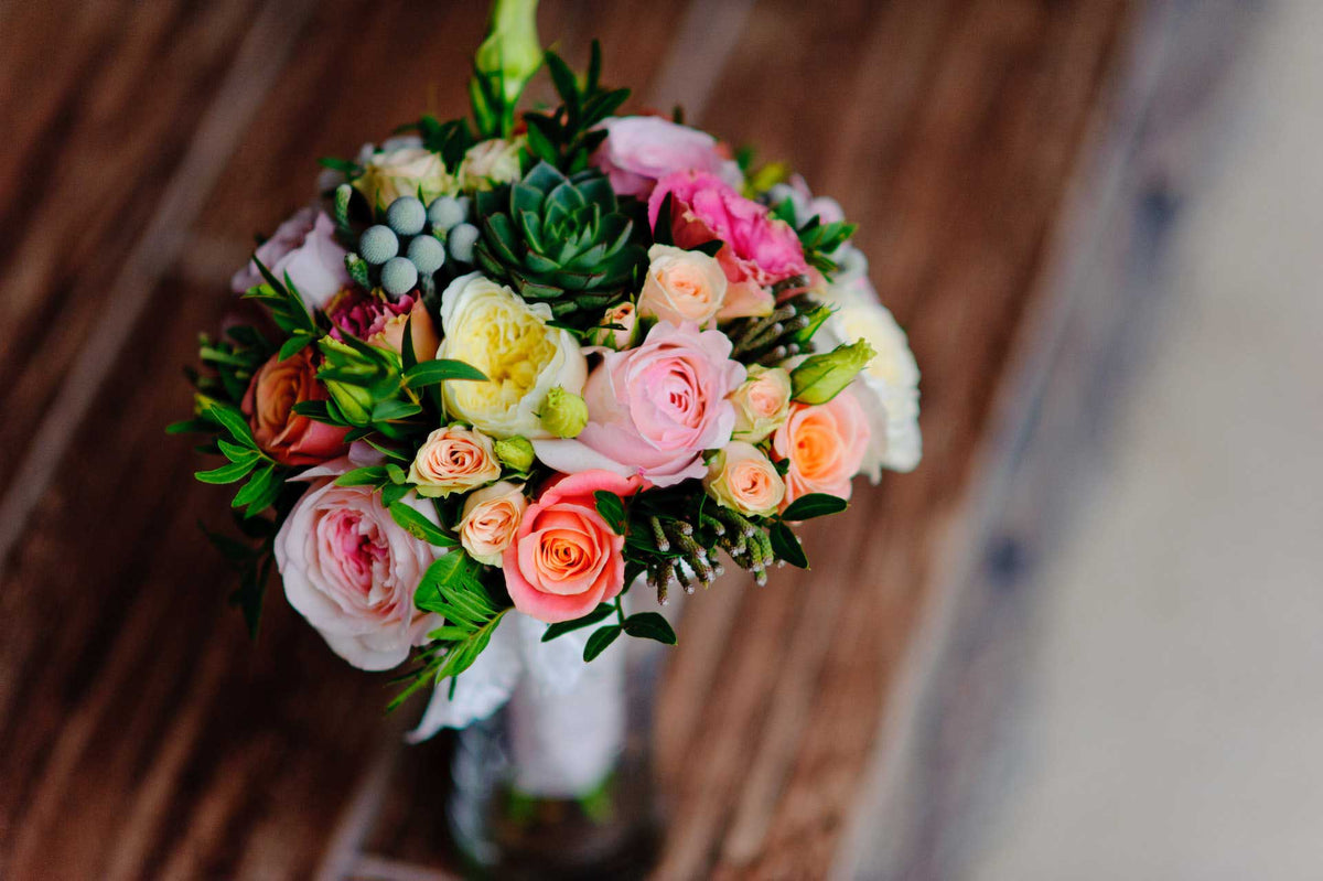 Handcrafted bouquet of pink and peach roses with fresh greenery
